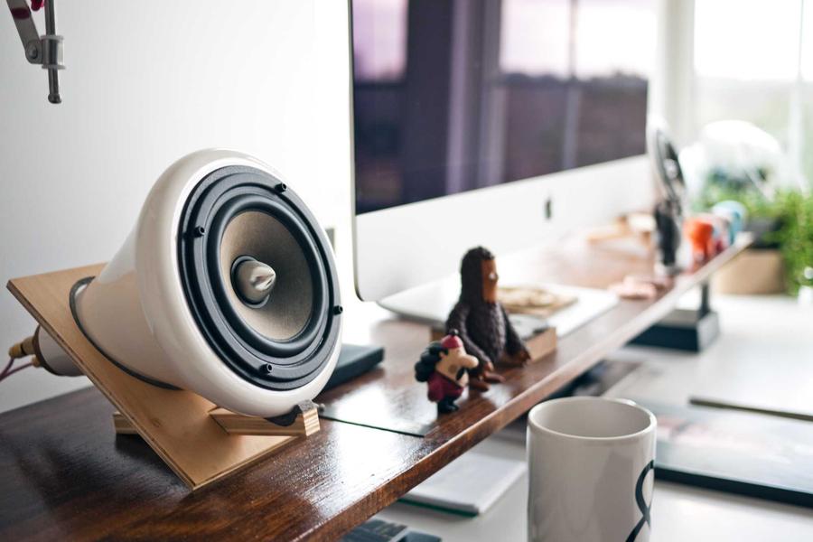 A desk with a computer monitor and studio speaker